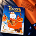 Terry's Chocolate Orange 106g Advent Calendar on navy bookcloth beside orange wrapping paper embossed with The Great British Shop logo